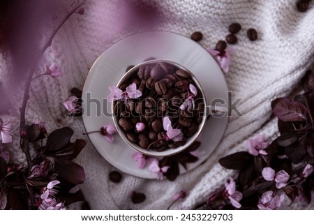Cup of coffe beans and pink flowers
