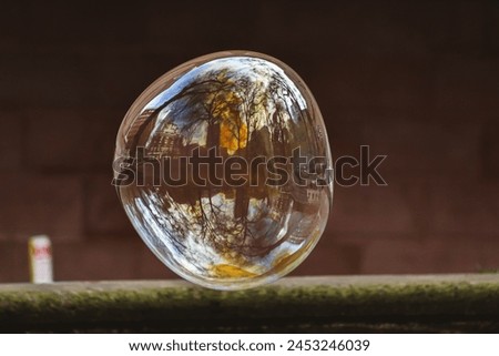 A delicate soap bubble, iridescent with hues of blue, green, and purple, hovers above a weathered sidewalk. Its spherical form reflects the surrounding cityscape, creating a mesmerizing interplay.