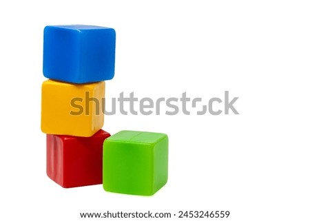 Multicolored plastic cubes for children's games. Yellow cube stands on top of red and blue cube, green cube stands next to it. One on one. High quality photo. Royalty-Free Stock Photo #2453246559