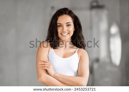 Smiling millennial pretty brunette lady wearing top proudly showing her healthy skin in a bright bathroom setting Royalty-Free Stock Photo #2453253721