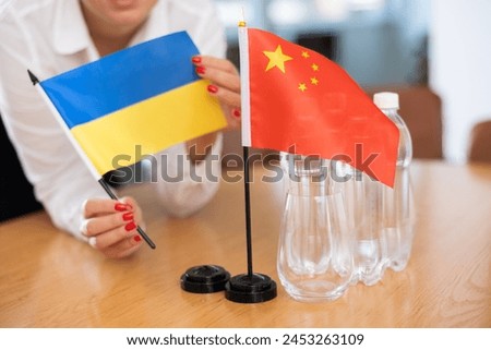 Small flags of Ukraine and China on negotiating table in office space