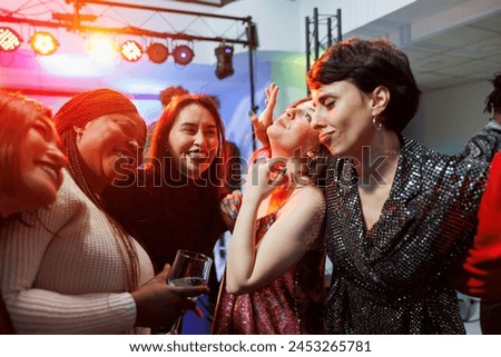 Cheerful smiling women drinking alcohol, hugging and partying together in nightclub. Carefree diverse girlfriends holding beverage glasses, laughing and having fun in club Royalty-Free Stock Photo #2453265781