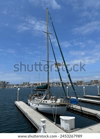Cutter sailboat docked at a small marina by itself flying small american flag Royalty-Free Stock Photo #2453267989