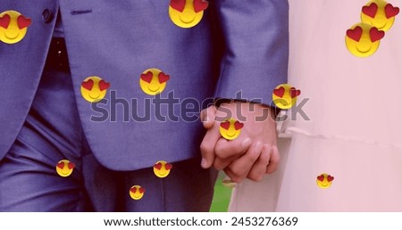 Image of multiple heart eyes face emoji floating against mid section of newly married couple holding hands. Happy Valentines Day celebration concept digitally generated image.