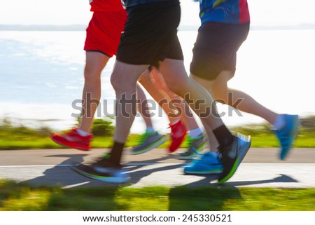 Group of runners compete in the race on coastal road. Blurred motion Royalty-Free Stock Photo #245330521