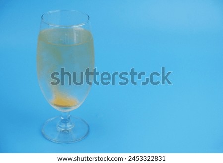 Vitamin C effervescent tablet dissolving in glass of water on blue background. Copy space for text.