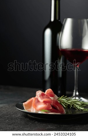 Prosciutto with rosemary and red wine on a black background. Copy space for your text.