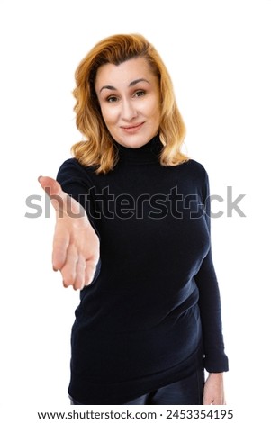 Portrait of forty year old woman offering handshake as greeting and welcoming, isolated on white background. Woman in black turtleneck smiling and posing in studio. Successful business.
