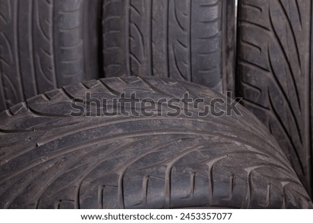 Automobile composition made up stack of tires and wheel with shiny disc in a car service before seasonal replacement or after breaking through. Royalty-Free Stock Photo #2453357077