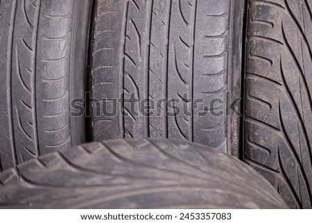 Automobile composition made up stack of tires and wheel with shiny disc in a car service before seasonal replacement or after breaking through. Royalty-Free Stock Photo #2453357083