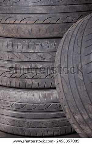 Automobile composition made up stack of tires and wheel with shiny disc in a car service before seasonal replacement or after breaking through. Royalty-Free Stock Photo #2453357085