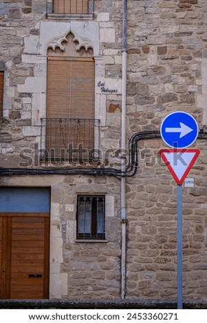 Moia, Spain - January 14, 2023: Facade of a historic building with a mandatory direction and yield traffic sign.