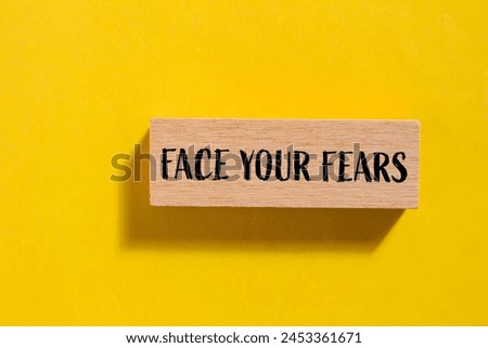 Face your fears words written on wooden block with yellow background. Conceptual face your fears symbol. Copy space.