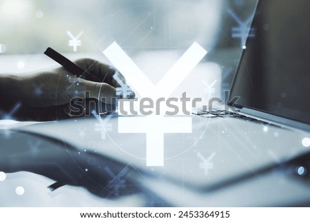 Creative concept of Japanese Yen symbol illustration and hand writing in notebook on background with laptop. Trading and currency concept. Multiexposure