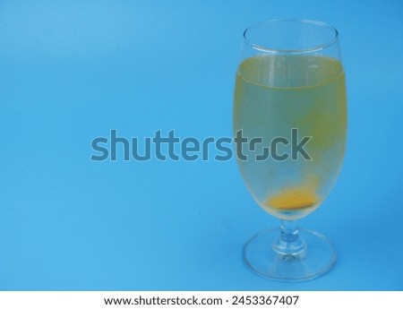 Vitamin C effervescent drug dissolving in water on blue background. Copy space for text.