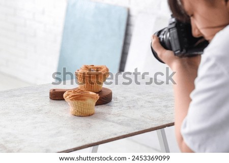 Female food photographer taking picture of cakes in studio, closeup