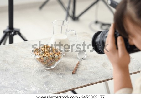 Female food photographer taking picture of cereal rings with milk in studio, closeup
