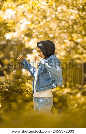Outdoor photoshoot at the green garden with casual outfit. Beautiful young women of Asian wearing hijab.