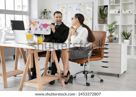 Happy office workers sitting at table with cocktails and world map in office. Summer vacation concept