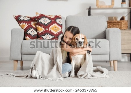 Cute little Asian girl with Beagle dog watching TV at home