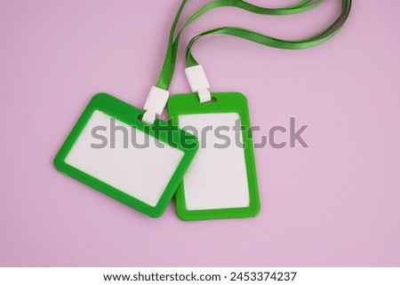Two blank green badges with ropes on pink background