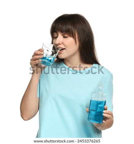 Young woman using mouthwash on white background Royalty-Free Stock Photo #2453376265