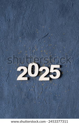Wooden number 2025 with golden tinsel on dark background. Happy New Year 2025 concept. Royalty-Free Stock Photo #2453377311