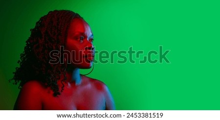 Profile portrait of elegant African woman with curly dark hair, well-kept skin posing on green studio background in neon. Concept of natural beauty, ethnicity, self-care, wellness, positive emotions Royalty-Free Stock Photo #2453381519