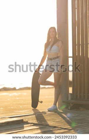 A woman is standing on a beach holding a skateboard