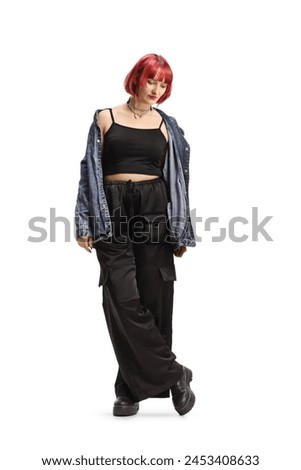 Young female with red heair wearing black wide trousers and denim shirt isolated on white background