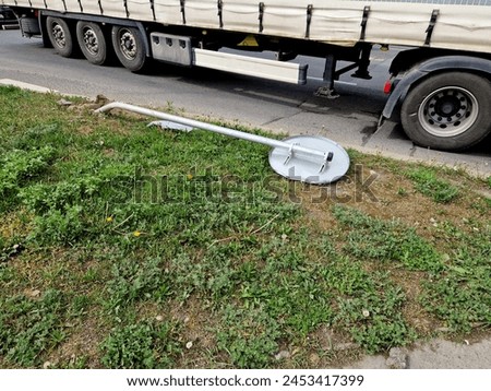 overturned traffic sign after a traffic accident. lies on the ground on concrete pavement behind a makeshift fence. Signs for car stops must stop at road junctions. accident prevention