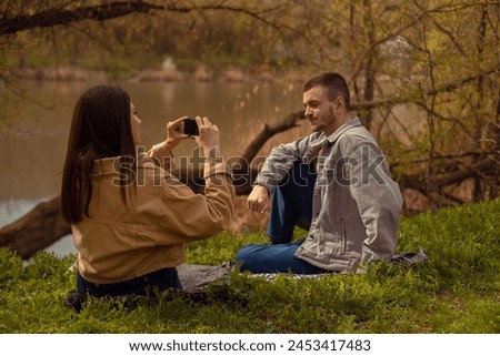 Young love: a teenage couple taking photos of each other on a phone. Capturing a touching moment on vacation, photo editing apps, travel routes, and tourist services.