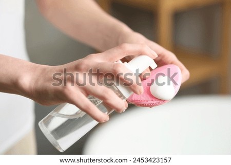 Washing face. Woman applying cleansing foam onto brush in bathroom, closeup