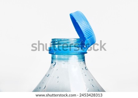 Close up of new cap attached to plastic bottle, connected to the neck of the bottle by solid tab attached to safety ring. They are intended to encourage recycling, as part of the fight against litter. Royalty-Free Stock Photo #2453428313