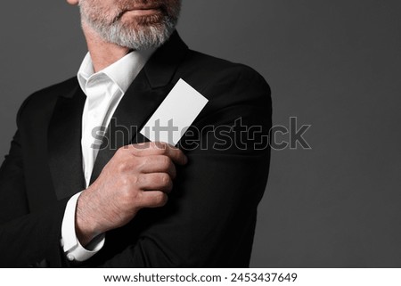 Man holding blank business card on grey background, closeup. Space for text
