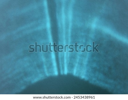 Abstract background semi circle or fan like pattern of sunlight refracted and reflected through an aquamarine or turquoise glass. Royalty-Free Stock Photo #2453438961