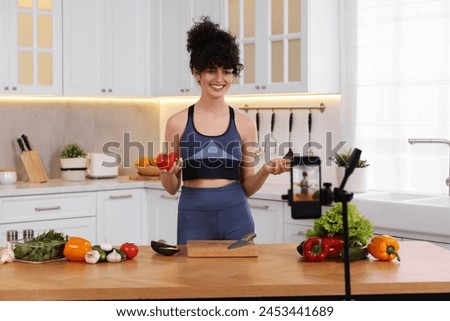 Smiling food blogger explaining something while recording video in kitchen Royalty-Free Stock Photo #2453441689
