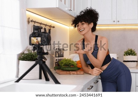 Smiling food blogger explaining something while recording video in kitchen Royalty-Free Stock Photo #2453441691