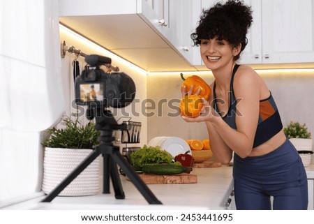 Smiling food blogger explaining something while recording video in kitchen Royalty-Free Stock Photo #2453441695