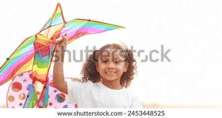 Little African-American girl flying kite outdoors. Banner for design