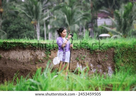 a woman creates content with a cellphone with a background of rice terraces