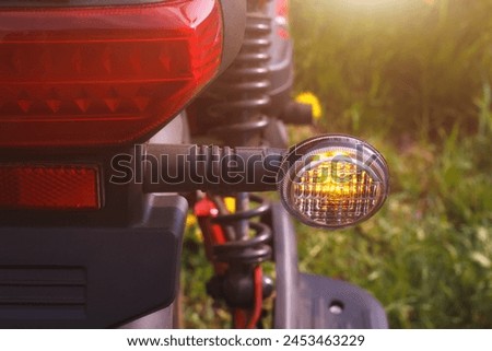 The right turn signal of scooter or bike parked on the roadside. The closeup view of direction safety signal with outdoors summer environment. Royalty-Free Stock Photo #2453463229
