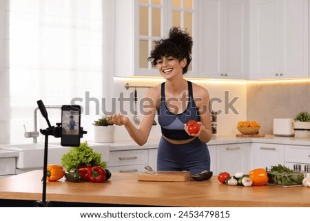Smiling food blogger explaining something while recording video in kitchen Royalty-Free Stock Photo #2453479815