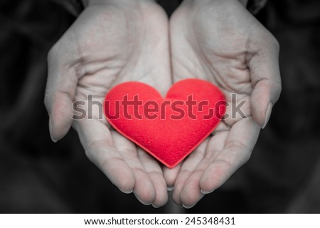 female hand holding fabric red valentine heart.