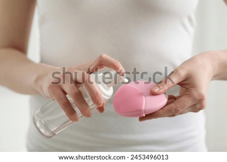 Washing face. Woman applying cleansing foam onto brush against light background, closeup