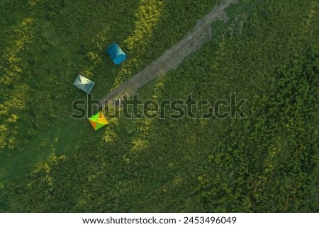 Aerial view of camping tents and bonfire on green meadow