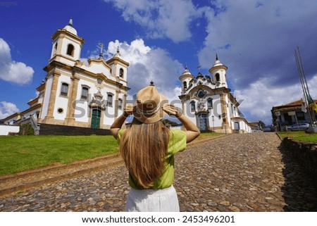 Tourism in Mariana, Minas Gerais, Brazil. Rear view of traveler woman visiting historical town of Mariana with baroque colonial architecture in Minas Gerais, Brazil. Royalty-Free Stock Photo #2453496201