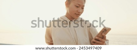 Close up, asian girl in sportswear uses the phone while standing on the embankment in the morning, Panorama
