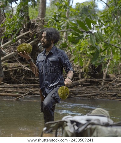 A man found a durian that had fallen and been swept away by river water in borneo jungle. Happy man. Durian lover.