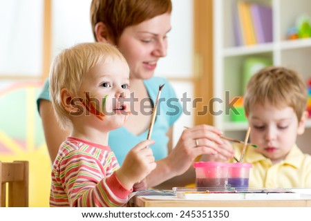 cute mother teaching her kids to paint